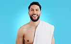 Shower, portrait and happy man in studio with towel for body care, wellness or grooming on blue background. Face, smile and model smile for beauty results, treatment or glow from bathroom routine 