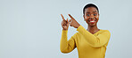 Happy black woman, portrait and pointing up for surprise, advertising or marketing against a gray studio background. African female person smile in wow for deal promotion, sale or discount on mockup