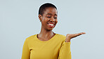 Happy black woman, smile and palm for advertising or marketing against a studio background. Face of African female person with hand out showing advertisement, product or presentation on mockup space