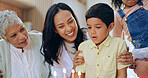 Boy with birthday cake, candles and big family to celebrate with smile, fun and love together in home. Happiness, surprise and congratulations, mom and grandparents at kids party with excited child.