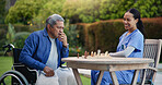 Happy woman, nurse and senior playing chess in nature for elderly care, match or thinking in strategic game. Female, medical caregiver or person with a disability contemplating next move on board