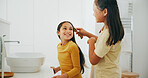 Family, bathroom and a girl brushing the hair of her sibling in their home for morning routine or care. Kids, smile or haircare with a happy young child and sister in their apartment for hygiene