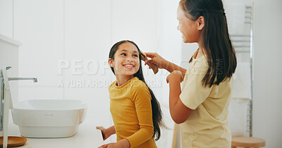 Buy stock photo Family, bathroom and a girl brushing the hair of her sibling in their home for morning routine or care. Kids, smile or haircare with a happy young child and sister in their apartment for hygiene