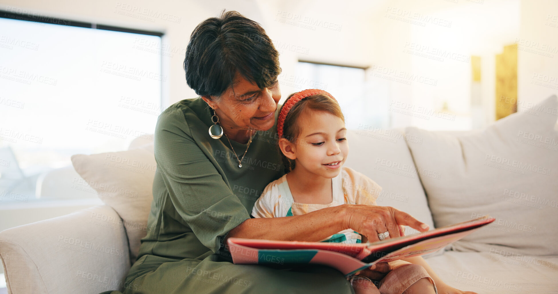 Buy stock photo Grandmother, child and reading book on sofa for literature, education or bonding together at home. Grandparent with little girl or kid smile for story, learning or relax on living room couch at house