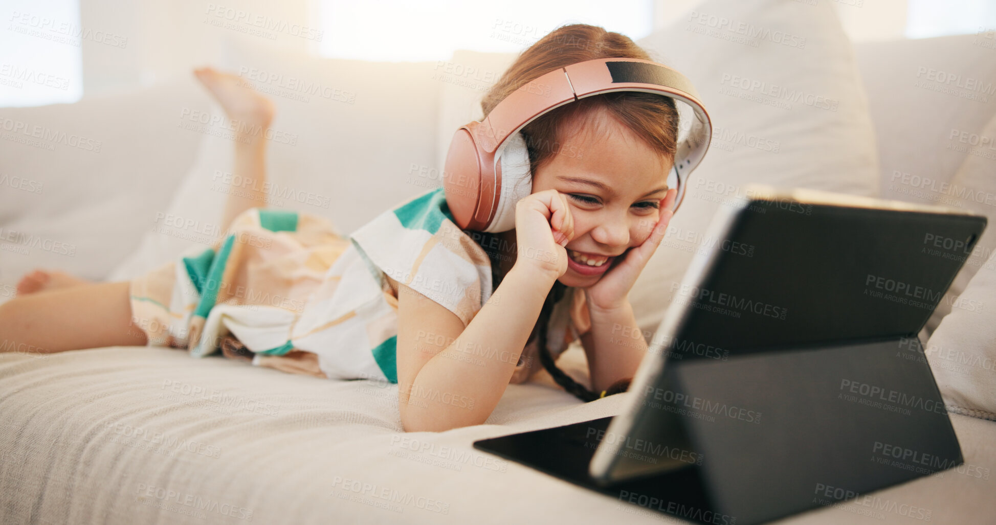 Buy stock photo Happy little girl, tablet and headphones on sofa for elearning, entertainment or streaming at home. Female person, child or kid smile on technology in relax for movie, education or learning at house