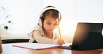 Little girl, headphones and writing in book for elearning, education or study on desk at home. Female person, child or kid taking notes with tablet, headset or technology for virtual class at house