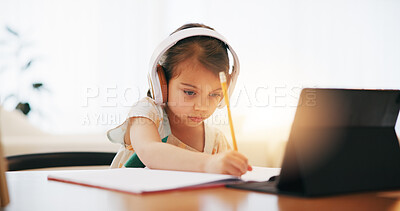 Buy stock photo Girl, headphones and writing in book for elearning, education or study on desk at home. Female person, child or kid taking notes with tablet, headset or technology for virtual class at house