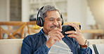 Senior, man and headphone with phone in living room for streaming, entertainment and mobile app. Elderly person, smile and retirement with technology with laugh for funny video, movie or film in home