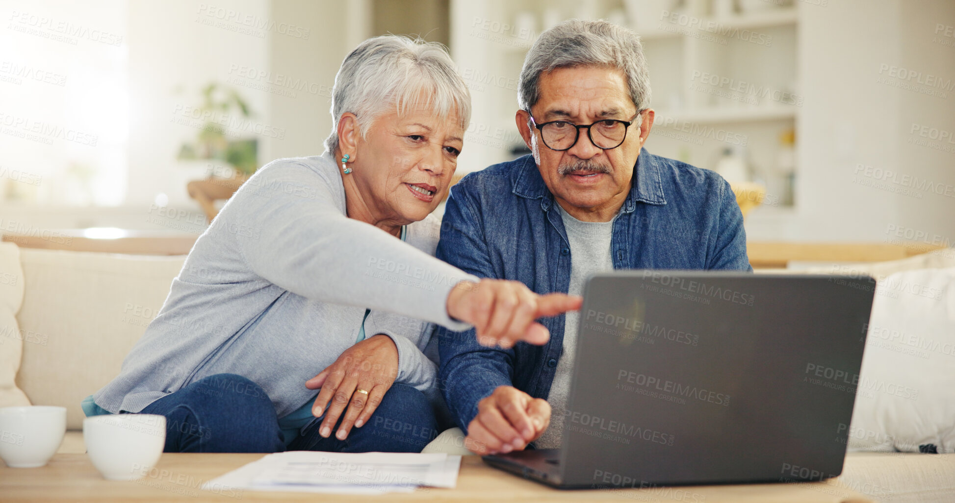 Buy stock photo Senior, couple and planning on laptop in living room with document for finances, investment or retirement. Elderly man, woman and pointing by technology for online banking, account balance or savings