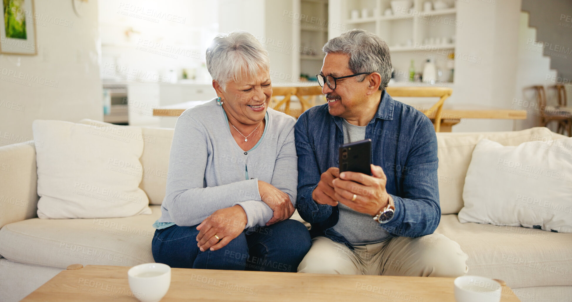 Buy stock photo Senior couple, cellphone and social media in living room sofa, conversation and smile. Grandparents, technology and communication for laughing, man and woman in retirement, happy and connection
