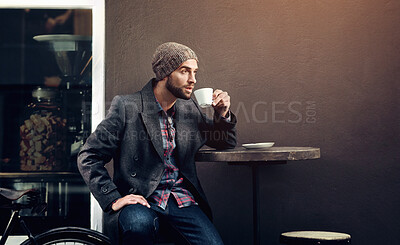 Buy stock photo Shot of a handsome young man in winter wear having a beverage at a sidewalk cafe