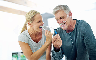 Buy stock photo Cropped shot of a mature man shaving his face while his wife brushes her teeth in the bathroom