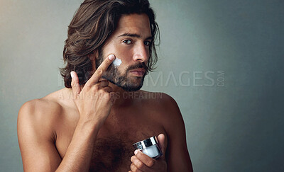 Buy stock photo Portrait, skincare or lotion with a shirtless man in studio on a gray background for his grooming routine. Beauty, facial and and the body of a handsome young person with antiaging cream for his skin