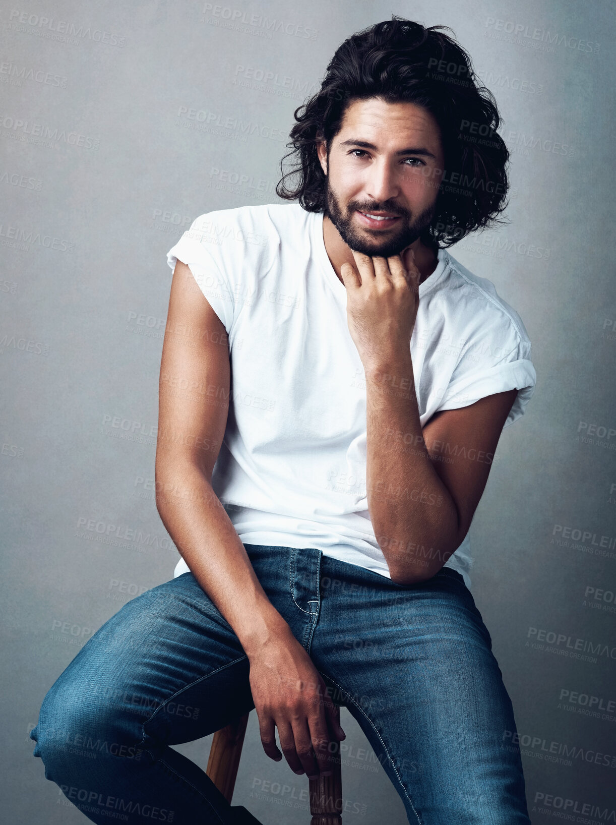 Buy stock photo Fashion, handsome and portrait of man in studio on a stool with casual, cool and stylish outfit. Happy, smile and confident young male model from Mexico with trendy style on chair by gray background.