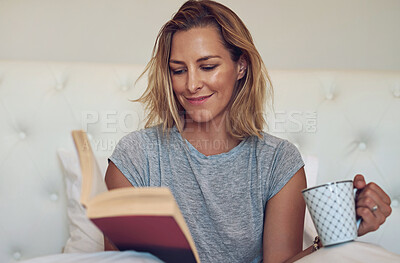 Buy stock photo Cropped shot of an attractive woman reading a book and drinking a cup of coffee in bed at home