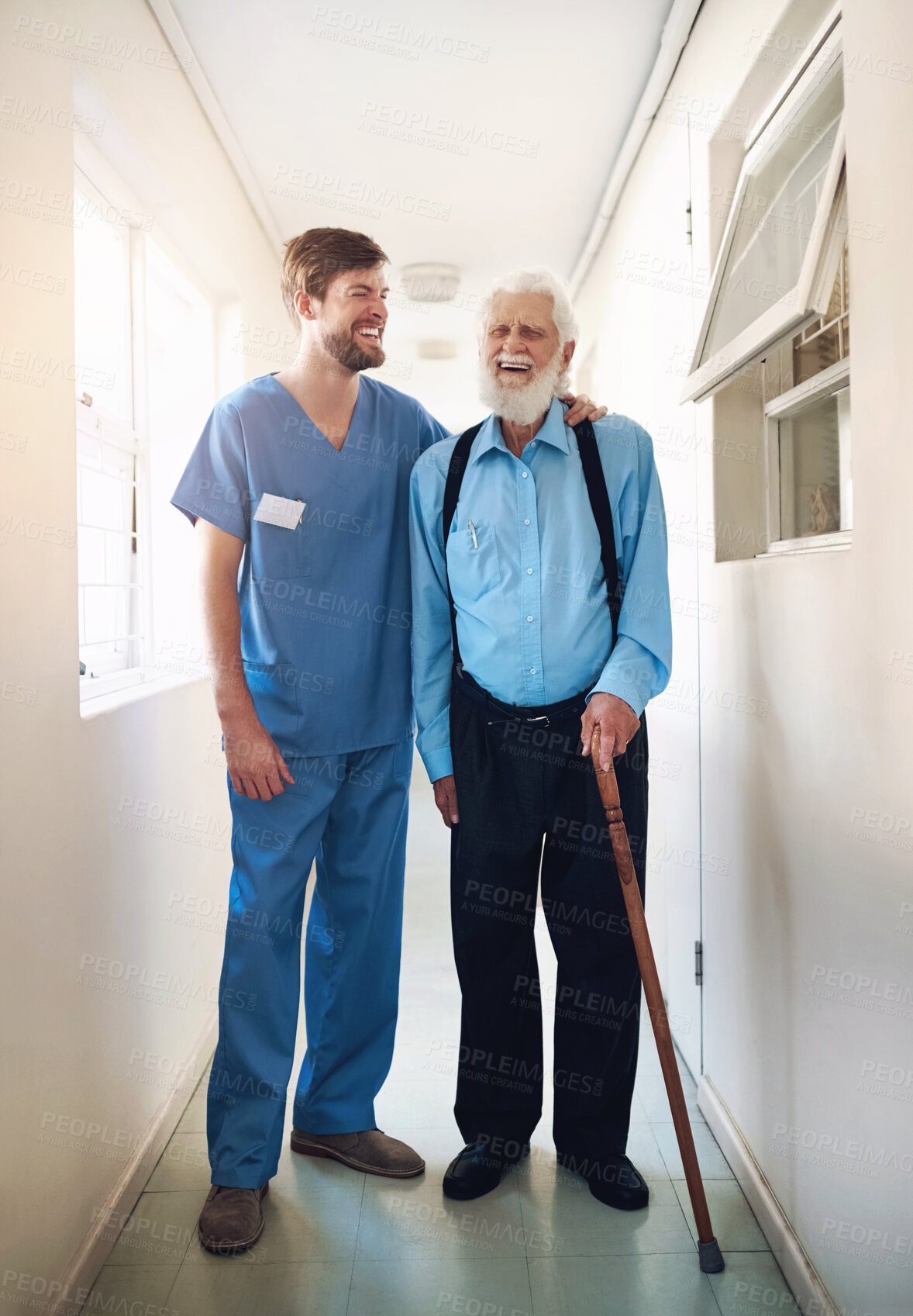 Buy stock photo Shot of a young doctor helping his senior patient walk down a hallway in hospital