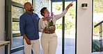 Couple, flowers and happy in new home or real estate with property investment, fresh start and support. Black people, man and woman with pot plant for pointing, moving and excited for achievement