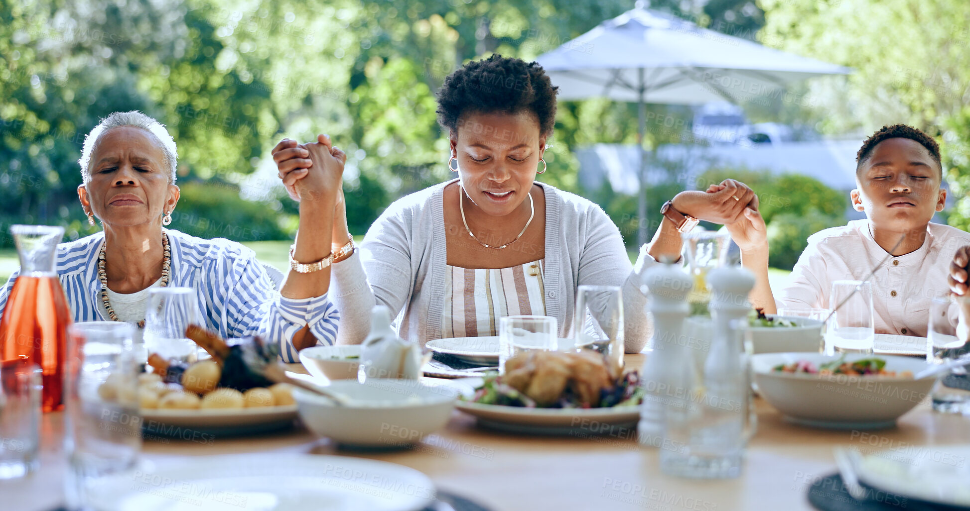 Buy stock photo Holding hands, black family or kid praying for food to worship God together for faith or gratitude. Grandmother, backyard or African mom with child in nature for a meal, brunch or lunch with grace