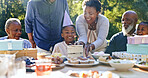 Young boy, birthday cake and wish in garden for party, happy family and celebration in nature. Black people, smile and cream dessert with fun with bonding, excited and special kid event in backyard