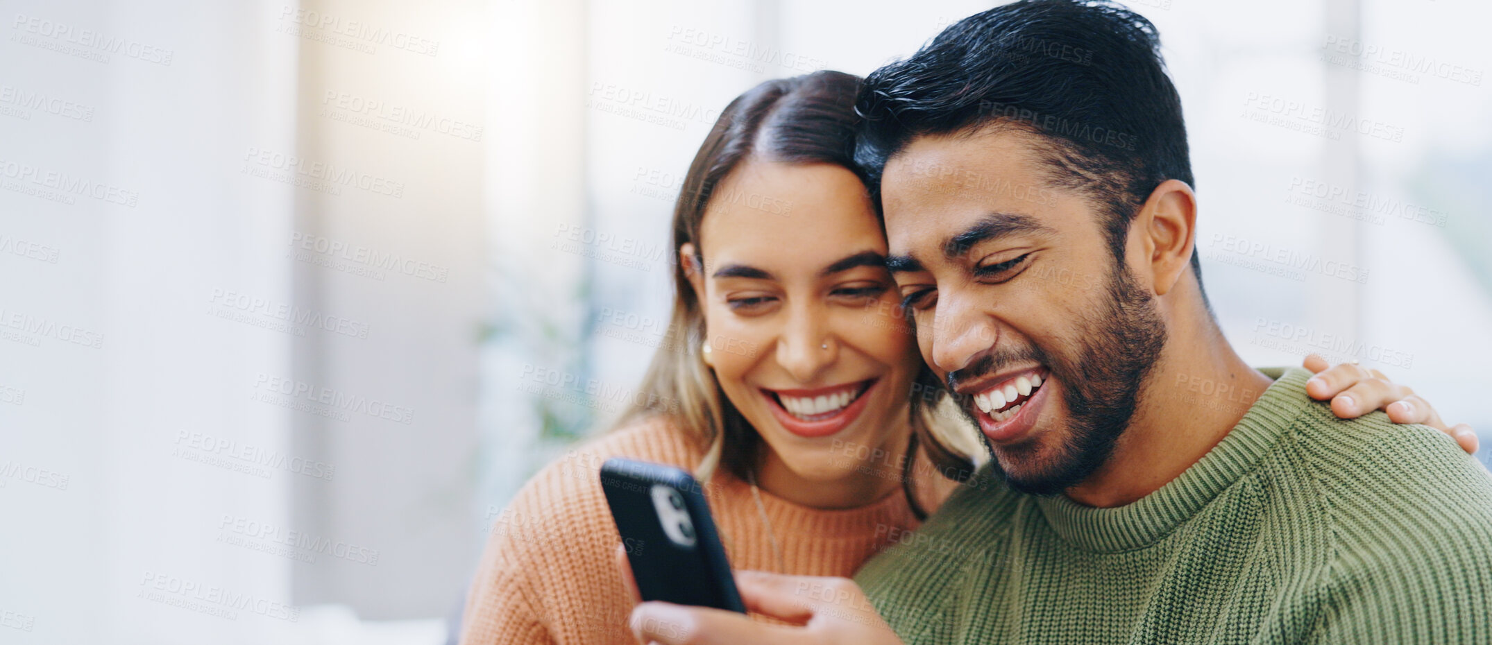 Buy stock photo Love, hug and happy couple with phone in a house for social media, streaming or checking meme in their home together. Smartphone, app and people smile in a living room for funny gif, text or chat