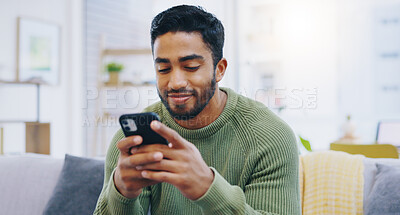 Buy stock photo Man, living room couch and texting with phone, smile and click for contact, meme and notification in home. Person, smartphone and happy for scroll, reading and app for social network, video and relax