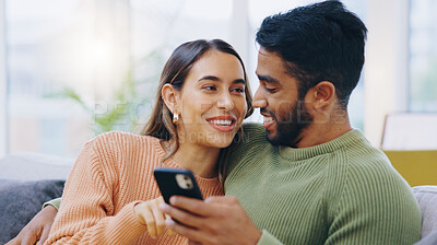 Buy stock photo Couple, phone and smile on sofa for social media, reading notification or scroll online shopping app at home. Happy man, interracial woman or smartphone to search digital news, mobile blog or website