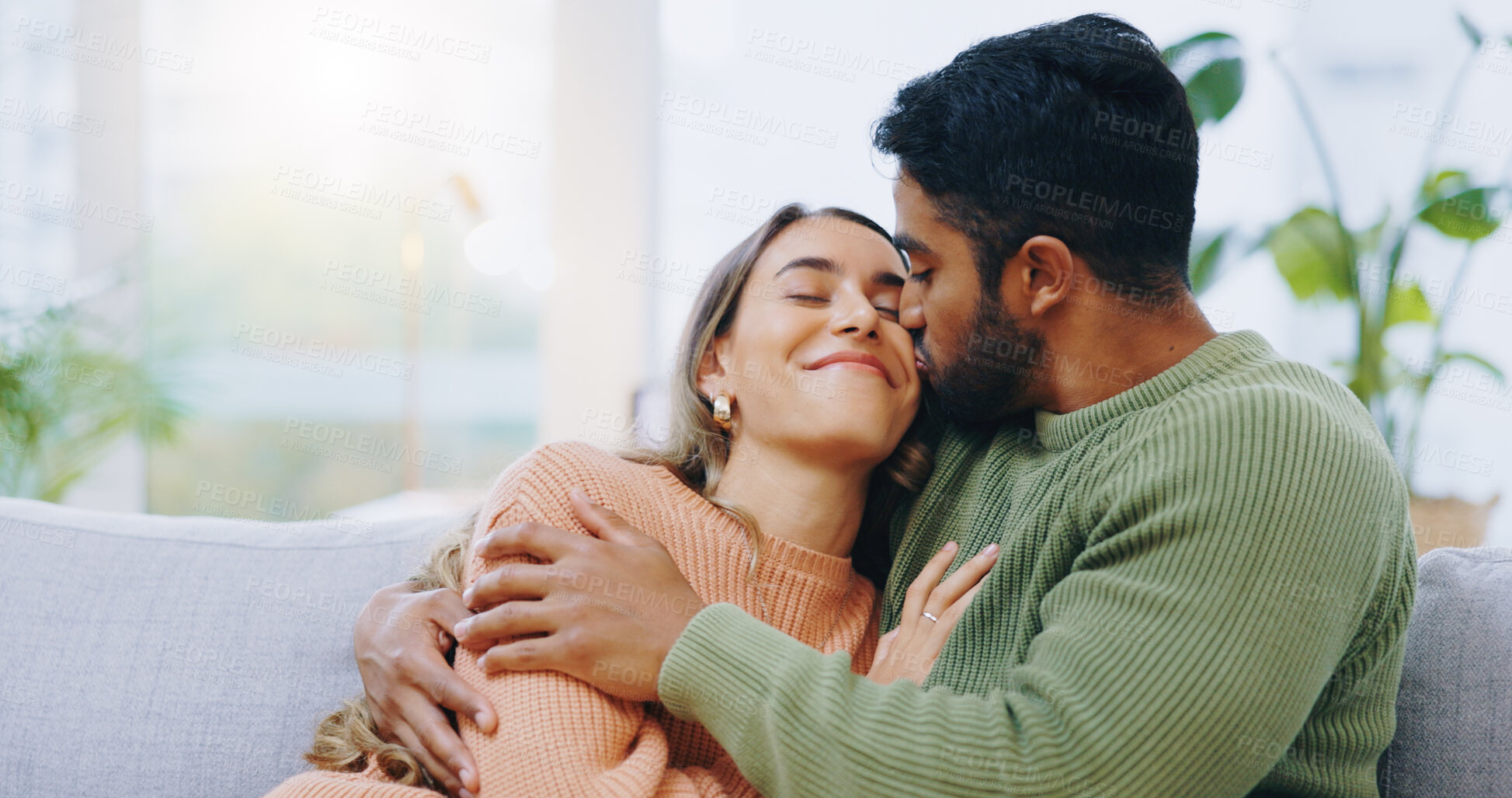 Buy stock photo Hug, kiss and couple on a sofa with love, relax and security at home bonding, hanging out or chilling. Happy, support and people in a living room with trust, commitment and gratitude, care or romance