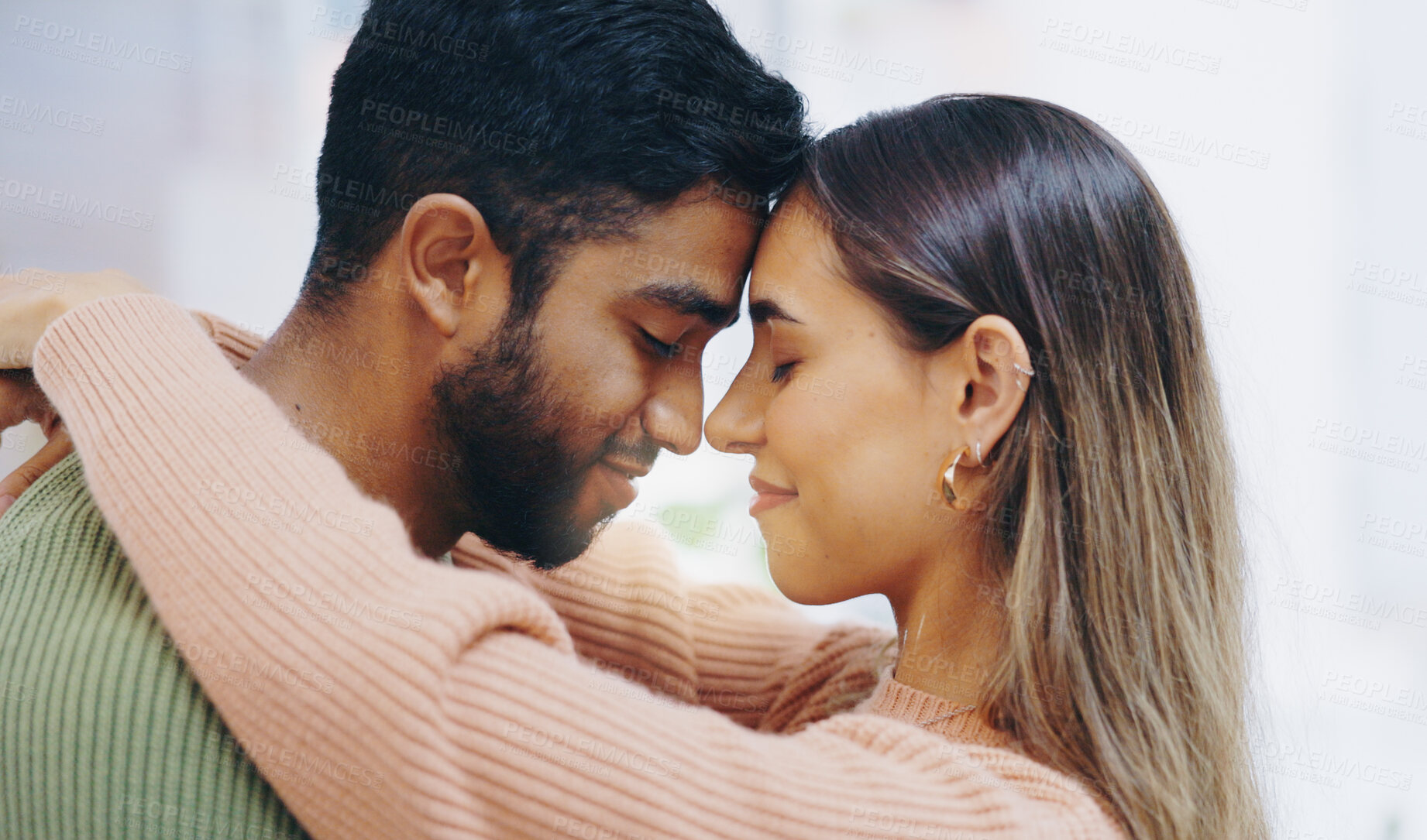 Buy stock photo Happy couple, forehead and hug in home for love, support and relax for care, romance and gratitude for partner. Face of young man, interracial woman and calm together for date, loyalty or anniversary