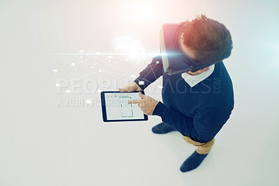 Buy stock photo High angle shot of a businessman wearing a VR headset while working on a digital tablet in an office