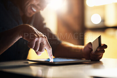 Buy stock photo Cropped shot of an unrecognizable male designer using his digital tablet to shop online while working in the office