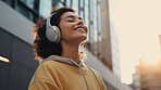 Young, woman and listening to music in city for entertainment, podcast and meditation. Beautiful, confident and happy student with fashion style, headphones and inspiration radio song on urban walk