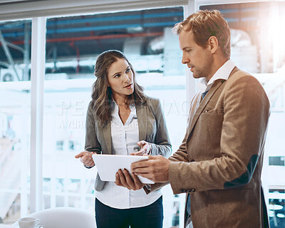Buy stock photo Cropped shot of two businesspeople working together on a tablet in their office