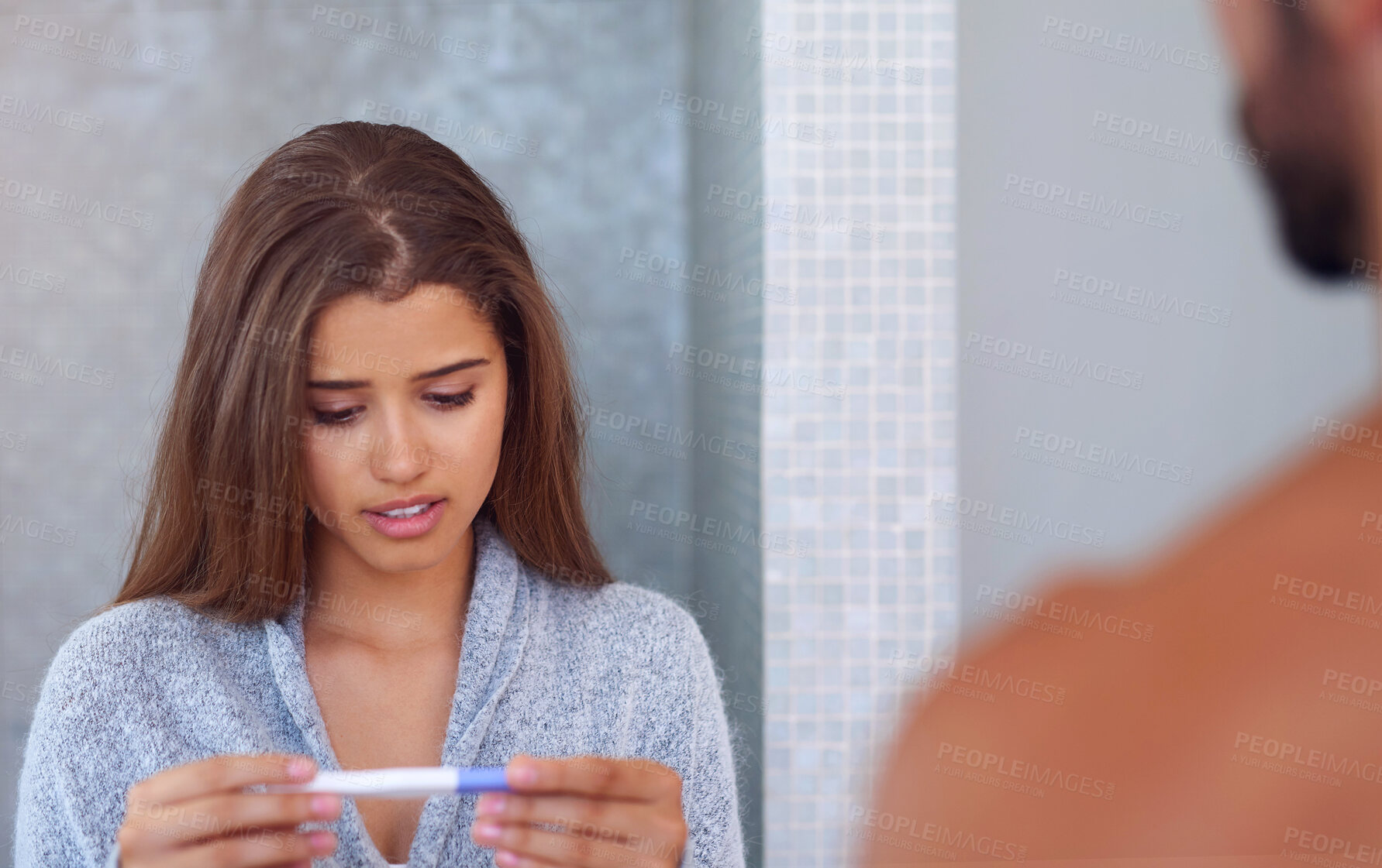 Buy stock photo Shot of a young couple looking worried while taking a pregnancy test at home