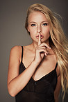 Woman, shush for secret in portrait, studio and mystery or confidential. Female person, finger and privacy for news, announcement and drama or information, face and emoji or icon by dark background
