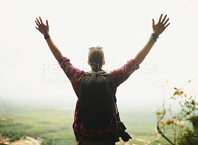 Buy stock photo Rearview shot of a young man standing atop a mountain with his arms outstretched