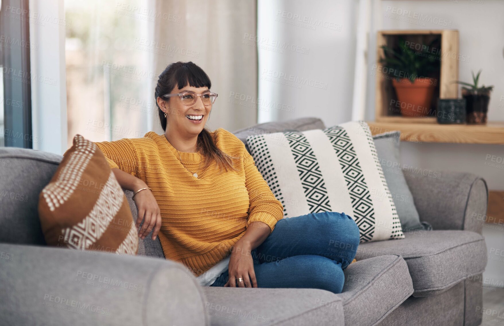 Buy stock photo Cropped shot of an attractive young woman sitting alone in her living room during a day off