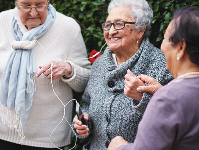 Buy stock photo Senior women, friends and earphones with music, listening and happy together in backyard with phone. People, retirement and smartphone for audio streaming subscription, podcast or radio in garden