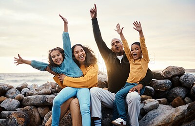 Buy stock photo Black family, parents and kids in beach portrait with hands in air, sitting and rocks with celebration. Black woman, man and children by ocean with love hug, care and bonding on holiday by sunset sky