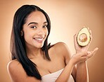 Face, smile and woman with avocado for skincare isolated on a brown background in studio. Portrait, fruit and model with food for nutrition, skin health and vegan diet, vitamin c or natural cosmetics