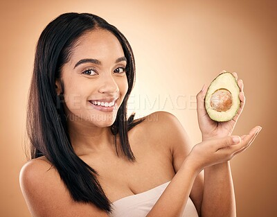 Buy stock photo Face, smile and woman with avocado for skincare isolated on a brown background in studio. Portrait, fruit and model with food for nutrition, skin health and vegan diet, vitamin c or natural cosmetics