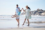 Family, mother and father with a child at the beach for fun, adventure and play on holiday. A happy woman, man and young kid walking on sand or swinging on vacation at the ocean, nature or outdoor