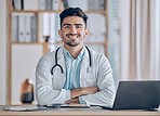 Happy, portrait and man doctor at desk in a healthcare, medical and hospital office. Smile, male professional and surgeon worker with arms crossed and computer feeling confident and pride in clinic 