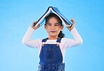 School, head and portrait of child with book for knowledge or learning isolated in a studio blue background. Clever, smart and young girl kid with notebook happy for education, story or reading