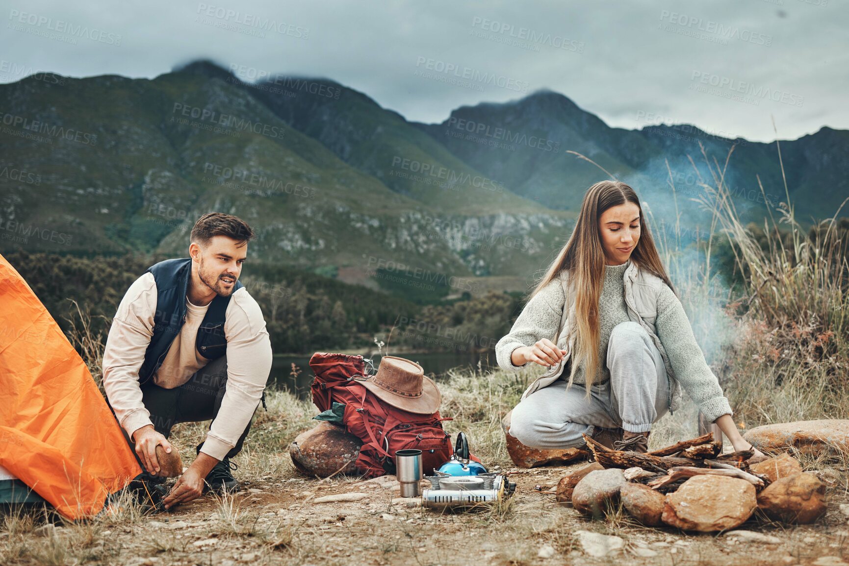 Buy stock photo Couple, camping and pitch tent in nature for vacation, holiday and travel together. Campfire, man and woman outdoor in preparation for adventure, hiking and trekking in the countryside for freedom