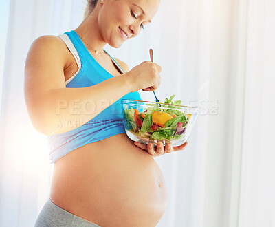 Buy stock photo Shot of a fit pregnant woman eating a bowl of salad at home