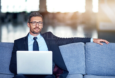 Buy stock photo Portrait of a confident businessman using his laptop while sitting on a couch in the office