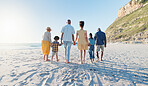 Holding hands, walking and big family at the beach on holiday, adventure or vacation together. Love, travel and children with parents and grandparents on the sand by the ocean or sea on weekend trip.