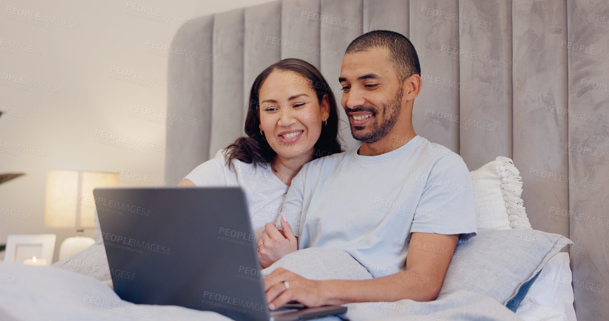 Buy stock photo Laptop, smile and young couple in bed watching movie, film or show together at home. Happy, technology and man and woman relaxing in bedroom streaming a video on computer for bonding at modern house.