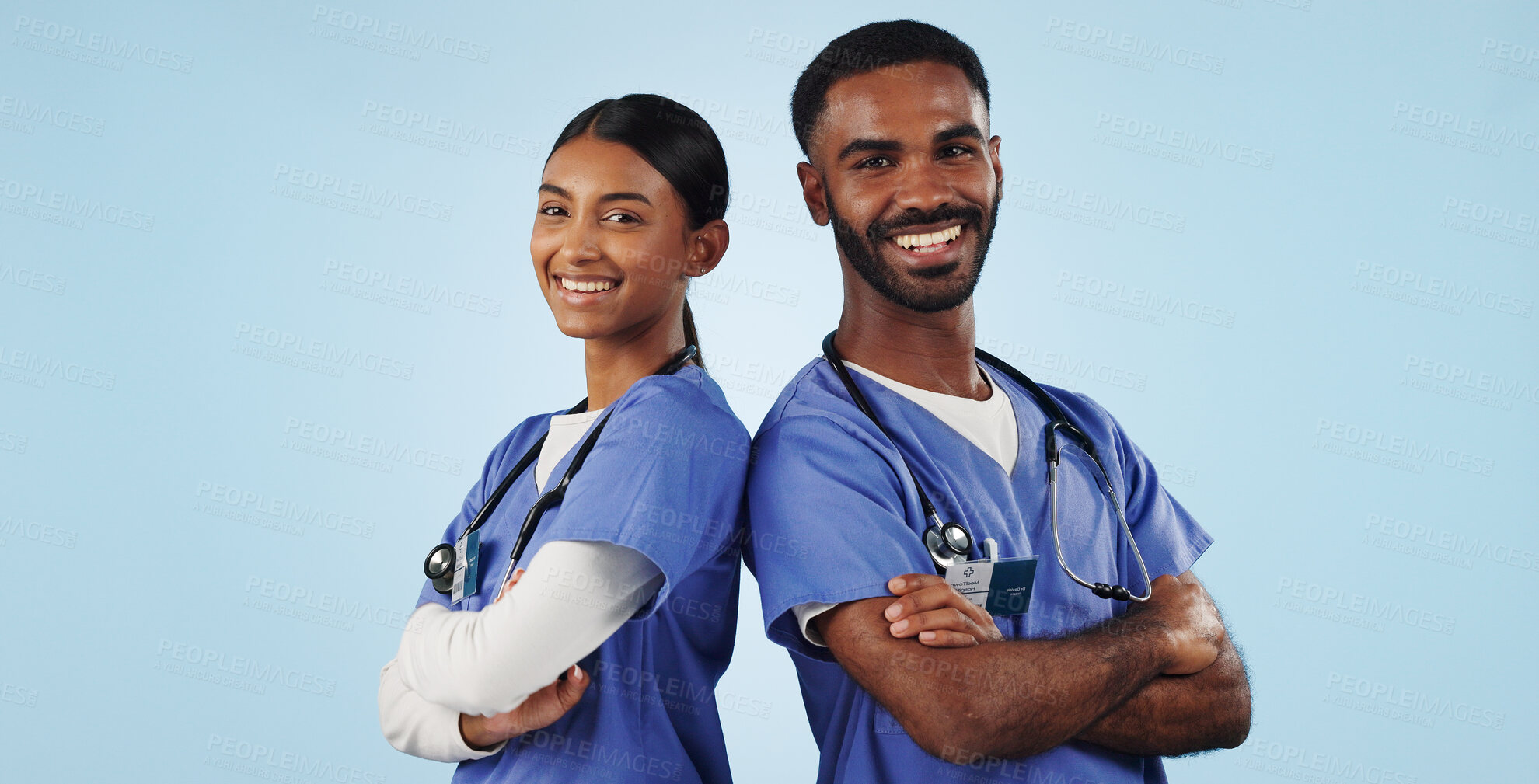 Buy stock photo Portrait, healthcare and arms crossed with a medicine team in studio on a blue background for trust. Medical, smile or wellness with a young man and woman nurse looking confident for treatment