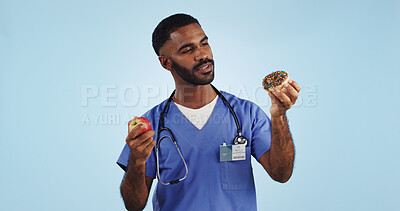 Buy stock photo Doctor, man and studio for donut, apple and choice with thinking for healthcare by blue background. Medic, person or nutritionist with decision, cake and fruit with ideas for food, eating and diet